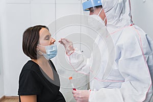 A doctor doing a PCR to detect Covid 19 on a pregnant woman in the doctor`s office.