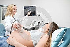 Doctor doing ultrasound exam of pregnant woman`s abdomen.