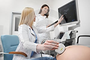 Doctor doing ultrasound examination of pregnant woman.