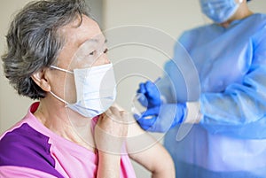 Doctor doing vaccine injection to senior woman