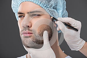 doctor drawing lines for facelifting on man,