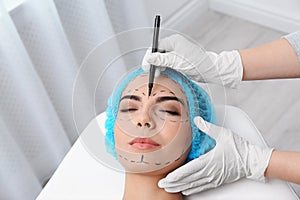 Doctor drawing marks on woman`s face for cosmetic surgery operation
