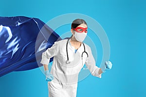 Doctor dressed as superhero posing on light blue background. Concept of medical workers fighting with COVID-19