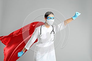 Doctor dressed as superhero posing on light grey background. Concept of medical workers fighting with COVID-19