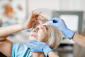 Doctor dripping eye drops on eyes of a senior patient