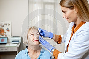 Doctor dripping eye drops on eyes of a senior patient