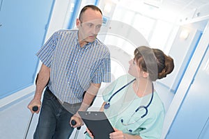 Doctor encouraging patient to walk with crutches