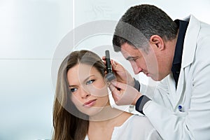 Doctor ENT checking ear with otoscope to woman patient