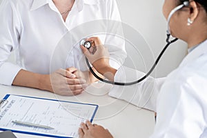 Doctor evaluates the patient with a stethoscope, blood pressure monitor and records the results
