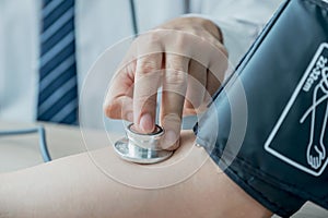 Doctor evaluates the patient with a stethoscope, blood pressure monitor and records the results, health medical checkup concept