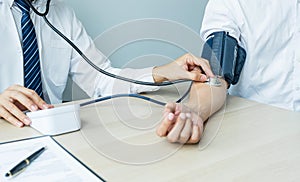 Doctor evaluates the patient with a stethoscope, blood pressure monitor and records the results, health medical checkup concept