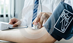 Doctor evaluates the patient with a stethoscope, blood pressure monitor and records the results, health medical checkup concept