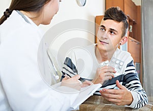 Doctor examinating teen boy with quinsy at home photo