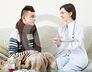 Doctor examinating teen boy with quinsy at home photo