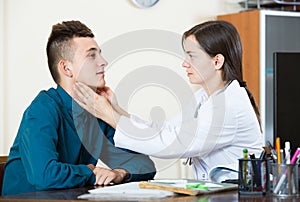 Doctor examinating teen boy with quinsy at office photo