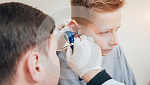 Doctor examines boy ear with otoscope. Medical equipment.