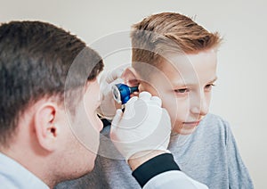 Doctor examines boy ear with otoscope. Medical equipment.