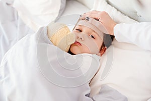 Doctor examines child fever with hand on forehead.