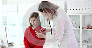 Doctor examines child girl in medical office with stethoscope