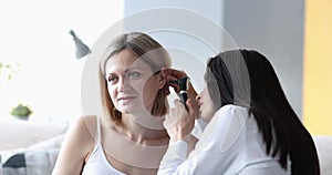 Doctor examines ear of adult woman closeup