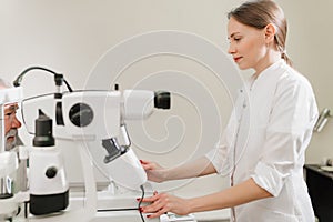 doctor examines eyes on screen of autorefractometer.