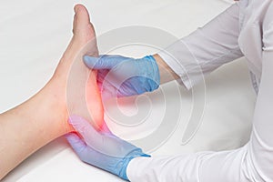 Doctor examines the leg of the woman heel for heel spurs, pain in the foot, plantar fasciitis, osteophyte