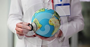 Doctor examines model of Earth with stethoscope in hospital