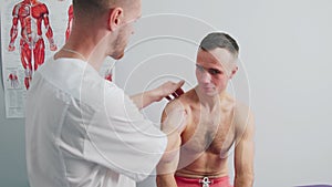 The doctor examines the patient. The man complains of body pain. Shoulder injury