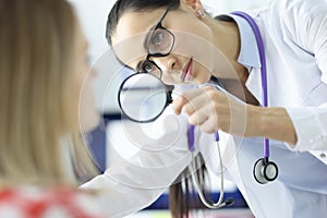 Doctor examines the patient`s face through magnifying glass