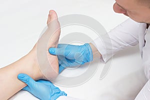 Doctor examines the patient`s leg with heel spurs, pain in the foot, white background, close-up, plantar fasciitis photo