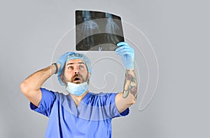 Doctor examines radiographic snapshot of wrist. Surgeon estimate damages. Hospital emergency. Doctor compares results. X photo