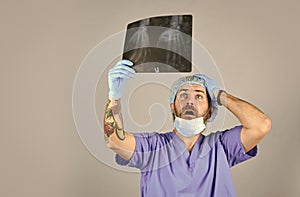 Doctor examines radiographic snapshot of wrist. Surgeon estimate damages. Hospital emergency. Doctor compares results. X photo
