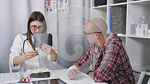The doctor examines an x-ray of the patient`s arm. A patient with a bandaged wrist sitting in the doctor`s office.