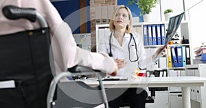 Doctor examines an x-ray of patient in wheelchair