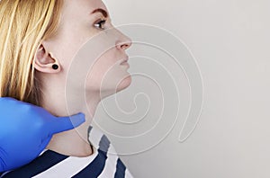 The doctor examines the thyroid gland of a girl. Hands in gloves feel the cartilaginous protrusion of the larynx