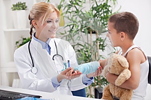 Doctor examines, young boy wearing a blue cast