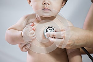 Doctor examining asian baby girl and listen her heart beat