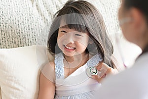 Doctor examining an asian cute little girl by using stethoscope.