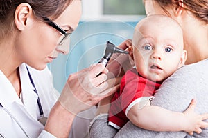 Doctor examining baby boy with otoscope