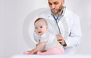 Doctor Examining Baby Listening To Her Lungs Over White Background