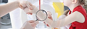 Doctor examining baby skin on hand with magnifying glass in clinic