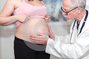 Doctor examining belly of pregnant woman