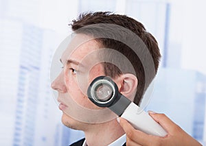 Doctor Examining Businessman With Dermoscope