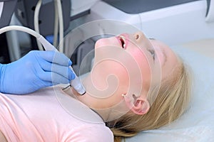 Doctor examining child girl thyroid gland using ultrasound scanner, closeup.