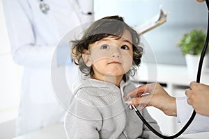 Doctor examining a child patient by stethoscope. Cute arab boy at physician appointment. Medicine and healthcare concept