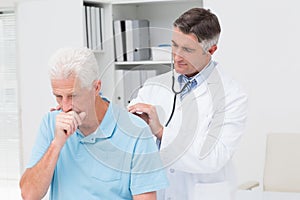 Doctor examining coughing senior patient