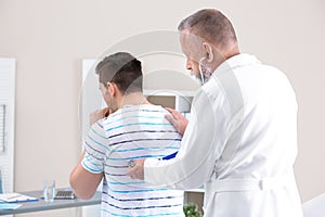 Doctor examining coughing young man