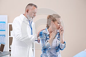 Doctor examining coughing young woman