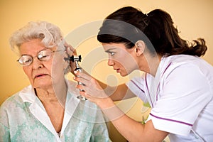 Doctor examining ear to senior woman