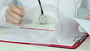 Doctor examining electroencephalogram, studying patient's brain activity, EEG